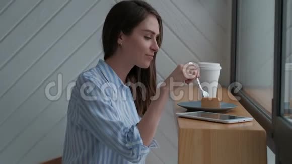 咖啡馆里的女人喝着热拿铁吃着芝士蛋糕视频的预览图