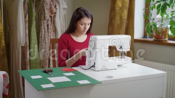 美丽的黑发女人正在调整缝纫机视频的预览图