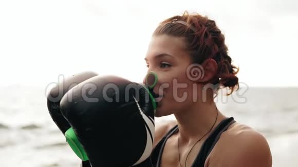口渴的女拳击手戴着手套休息一下训练后从水瓶里喝水美丽的女子训练视频的预览图