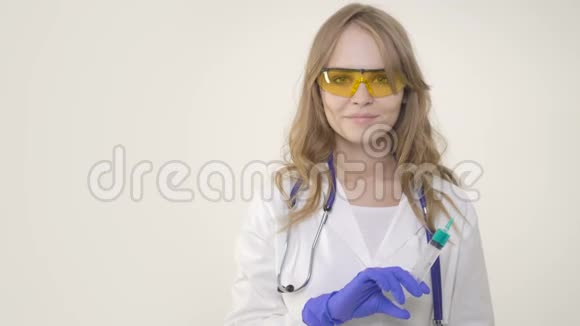 年轻的女医生微笑着拿着白色背景的注射器视频的预览图