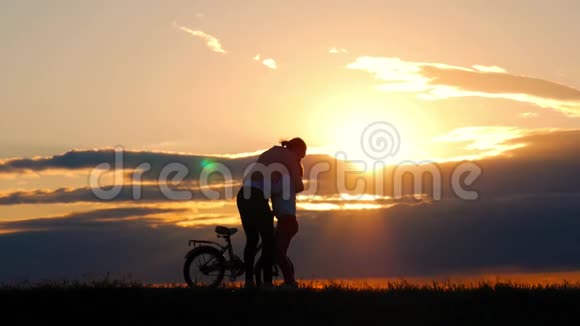 剪影自行车可爱的家庭在草地上日落时间母亲和婴儿在日落时骑自行车的剪影生活方式视频的预览图