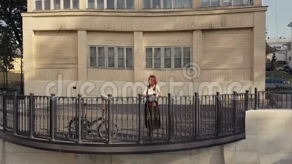 年轻女子站在阳台的豪宅中可以看到绿色城市公园的鸟瞰图视频的预览图