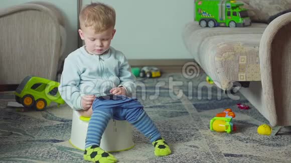 可爱的男孩带着智能手机在房间里的厕所训练视频的预览图