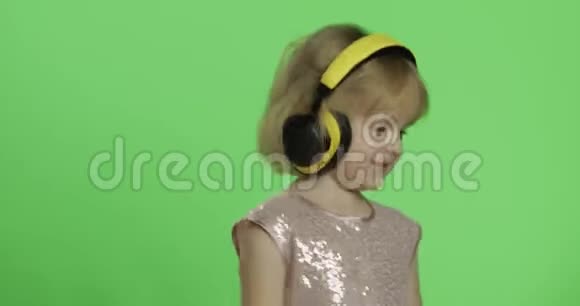 女孩穿着光滑的衣服和耳机听音乐和跳舞色度键视频的预览图