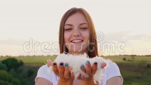 一个女人在手里吹羽毛羽毛和向下的方向相机视频的预览图