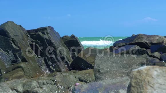 落基岸和溅起海水的蓝天景观海波在石滩破碎水的波浪在断裂视频的预览图