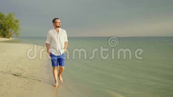一个穿着浅色衣服的孤独的人光着脚走在海边的沙滩上逃避关心自由和离开4慢视频的预览图