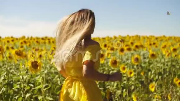 一个穿着黄色裙子的年轻女孩穿着向日葵奔跑慢动作视频的预览图