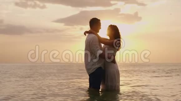 一对相爱的年轻夫妇在日落时站在海里看着对方视频的预览图