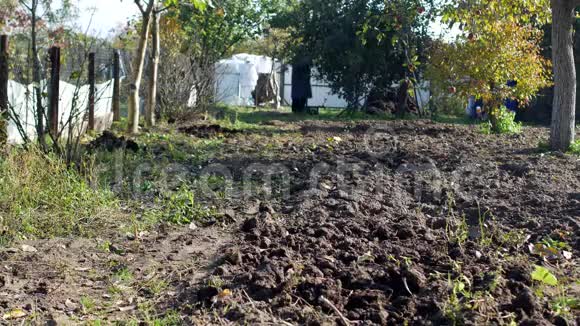 一个男人在乡村别墅区的嘎查里卷着一辆花园手推车来装肥料视频的预览图
