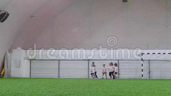 室内足球场小孩子在踢足球在战场上奔跑视频的预览图