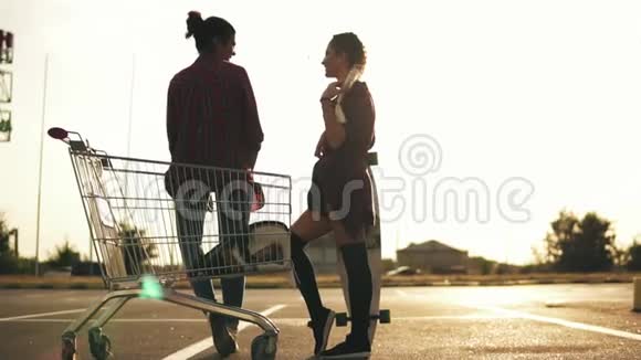 两个迷人的时尚女孩站在购物车边停车和交谈一个穿短裤的女孩视频的预览图