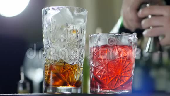 在玻璃杯中倒入冰块和近边的酒精即可得到明亮的鸡尾酒视频的预览图