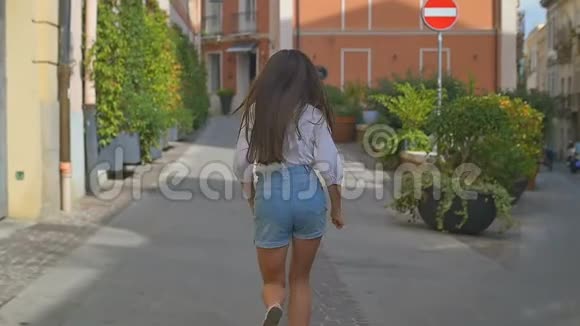 那个年轻的女人在旧城里奔跑是以老建筑为背景的镜头跟在后面慢动作视频的预览图