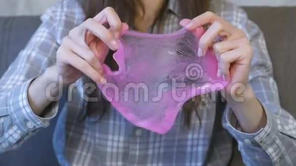 女人正在伸展粉红色的黏液和玩耍特写双手视频的预览图