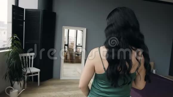 美丽的孕妇穿着绿色的纱裙有着美丽的妆容和发型靠近镜子看着视频的预览图