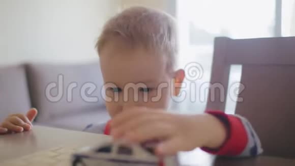 小男孩在桌旁玩玩具模型车视频的预览图