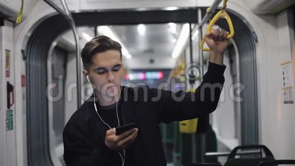 在公共交通中耳机听音乐和在手机上浏览的帅哥画像他握着视频的预览图