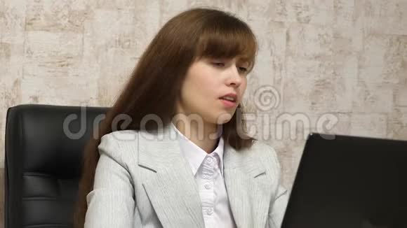 漂亮的女孩坐在办公室的椅子上用笔记本电脑打字年轻的女商人在电脑上工作女孩视频的预览图