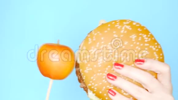 健康和不健康食品的概念雅洛科在明亮的蓝色背景上对抗汉堡包红色指甲的雌手视频的预览图