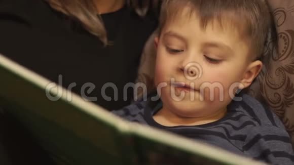 一个小男孩在卧室里躺在床上一起看书视频的预览图