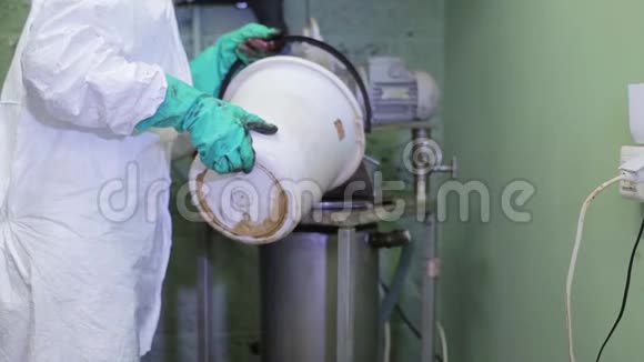 实验室工作人员将白桶中的水倒入工厂地下室的大钢罐中视频的预览图