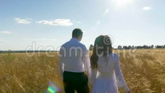 一男一女穿着白色西装带着麦子沿着田野走着视频的预览图