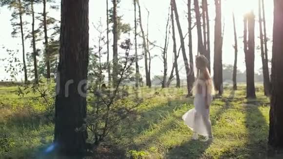 日落时分美丽的年轻女孩留着长发穿着白色连衣裙戴着帽子视频的预览图
