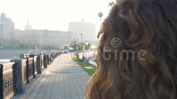 黎明时一个美丽的女孩沿着河堤散步阳光灿烂视频的预览图