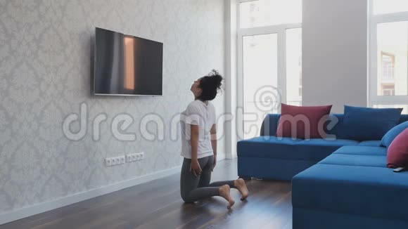 年轻的黑发女人靠在家里做运动视频的预览图