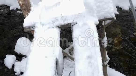 穿过一座白雪皑皑的木桥在群山中的河流上视频的预览图