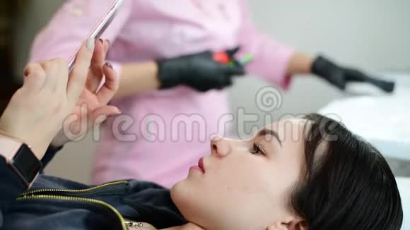 年轻女孩躺在沙发上在医疗程序前使用智能手机视频的预览图