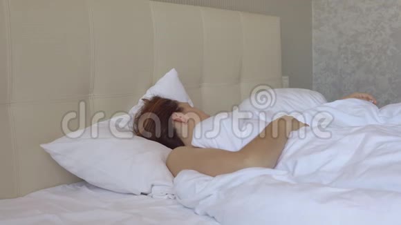 年轻漂亮的女孩在酒店的大床上醒来视频的预览图
