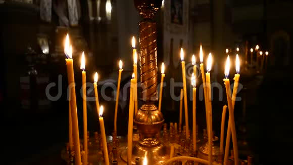 在基督教东正教教堂的其他蜡烛背景上点燃蜡烛特写视频的预览图