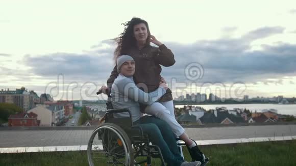 一位坐轮椅的快乐残疾人与户外年轻女子拥抱的肖像视频的预览图