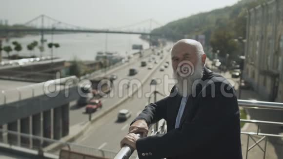 老人站在观景台上在城市道路和河流上欣赏风景视频的预览图