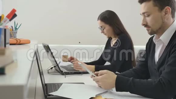 商人在办公室工作男人用平板电脑女人用笔记本电脑视频的预览图