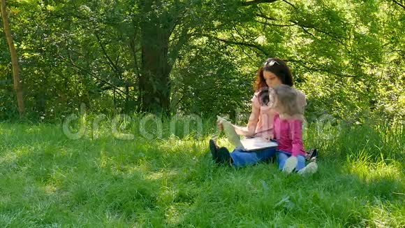 快乐的小女孩准备进入小学她的姑姑坐在城里新鲜的青草上视频的预览图