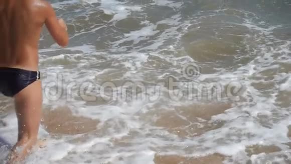 健康的男孩从海滩跳到海里视频的预览图