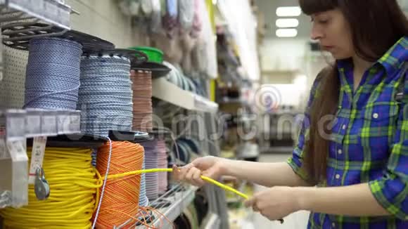 一个年轻的女人在建筑材料商店里选择一根绳子视频的预览图