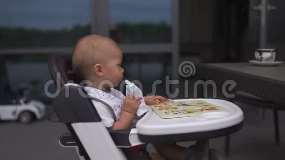 年轻的母亲喂养她的小儿子坐在孩子的座位上家庭价值观温暖的颜色夏天的场景视频的预览图