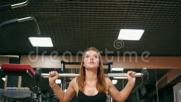 一位身材矮小的年轻女子在健身房里用杠铃做蹲改善了她的肌肉视频的预览图