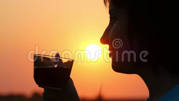一个女孩的脸与一杯茶或咖啡特写在日落背景女孩喜欢喝茶或咖啡视频的预览图