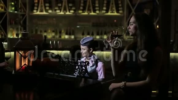 年轻女孩喜欢红酒和钢琴音乐在餐厅放松视频的预览图