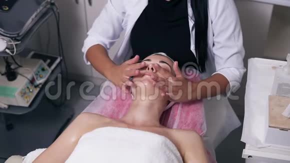 集中女性美容师正在水疗沙龙做面部按摩一个闭着眼睛的年轻女子躺在视频的预览图