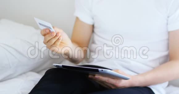 男子手持名片在家使用数码平板电脑视频的预览图