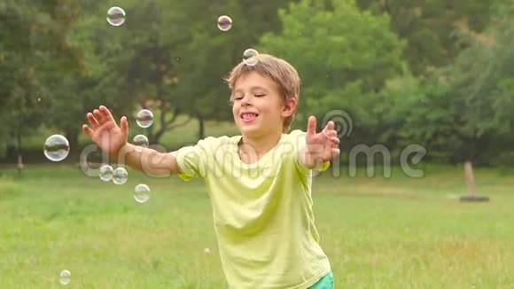 快乐男孩在花园里玩肥皂泡慢动作关门视频的预览图