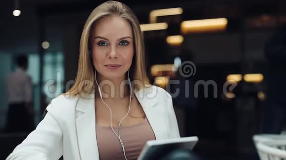 微笑的女人在商场里梳头看着平板电脑视频的预览图