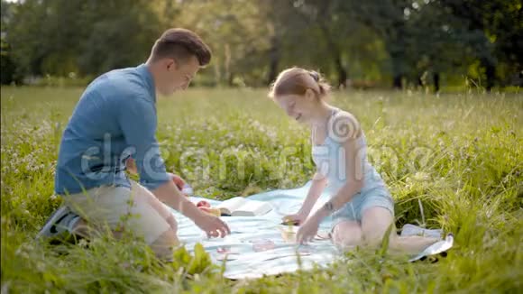 青少年快乐情侣在夏日户外野餐中玩纸牌游戏视频的预览图