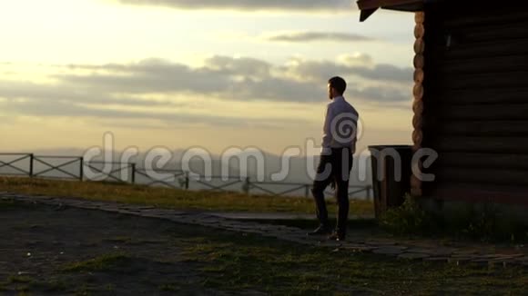 在日落时穿着西装的男人抱着花束走在小径上美丽的自然景观视频的预览图